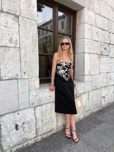a lady wears a scarf as a top with a black midi satin skirt